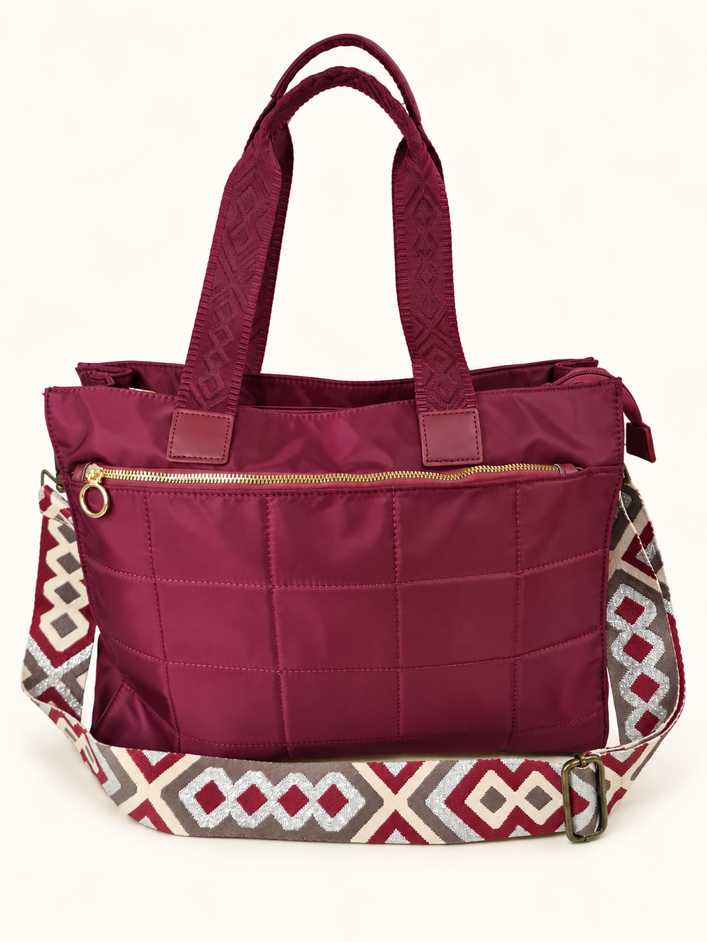 Bolso acolchado granate con asas y correa multicolor sobre fondo claro